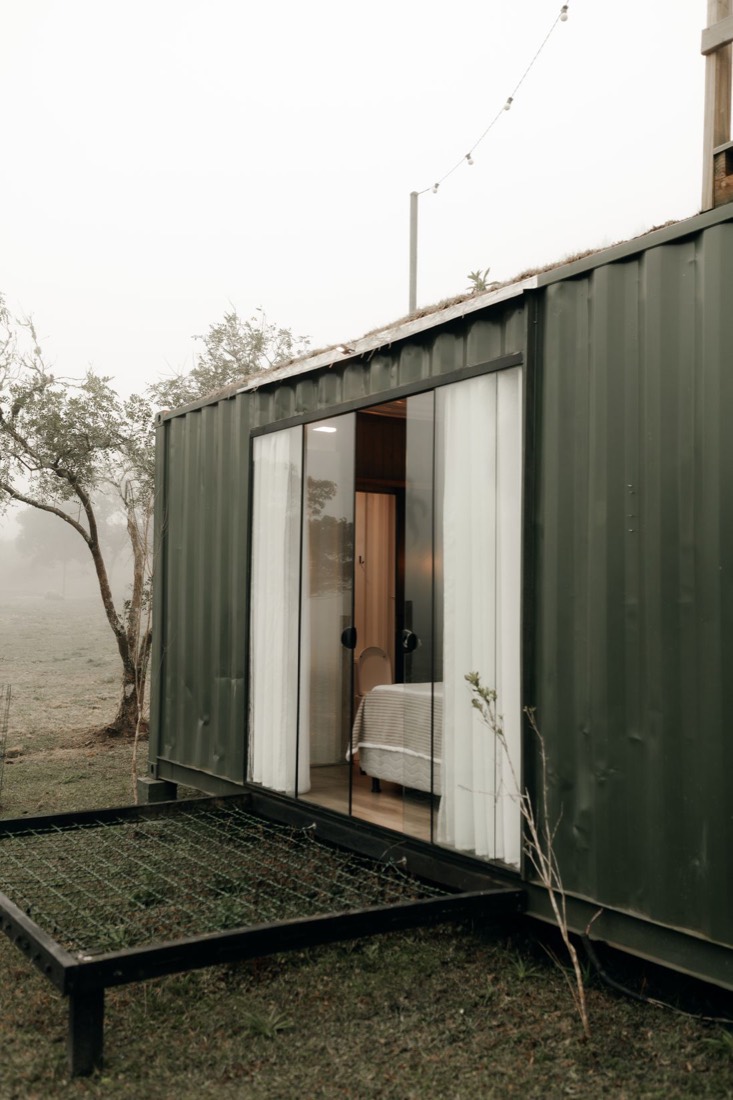 Casa contenedor habitacional con grandes ventanales rodeada de naturaleza